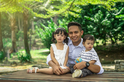 Portrait of father with children sitting against trees