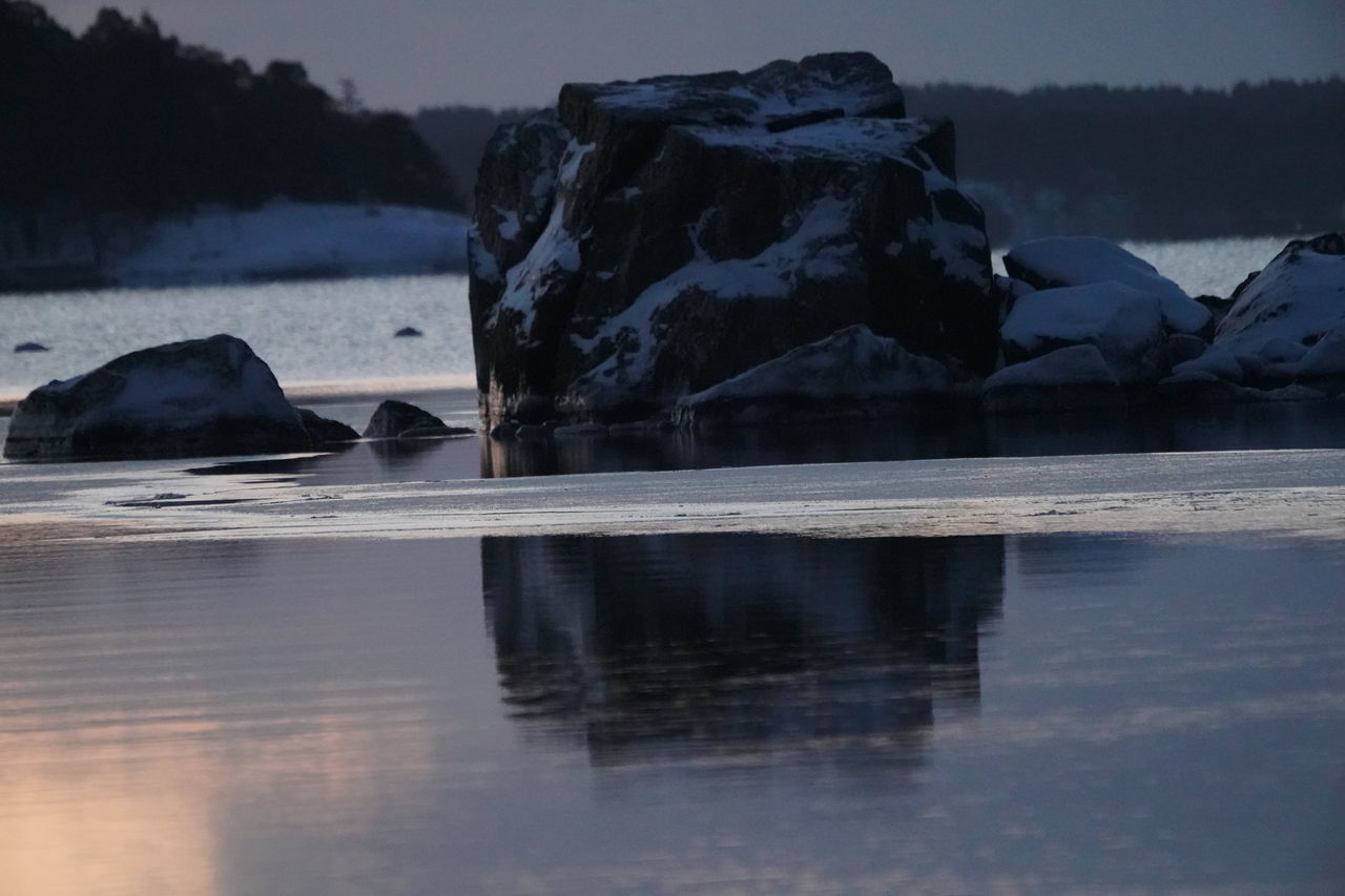 REFLECTION OF ROCKS IN WATER AGAINST SKY