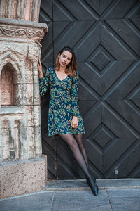 Portrait of young woman standing against wall