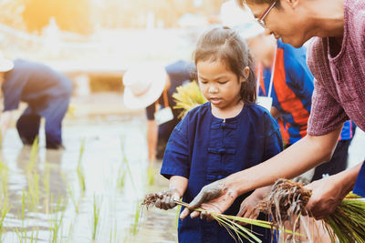 Father giving plants to daughter at farm