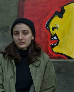 Portrait of teenage girl standing against graffiti wall