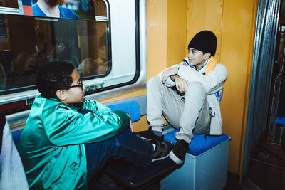 Male friends talking with each other while sitting in tram