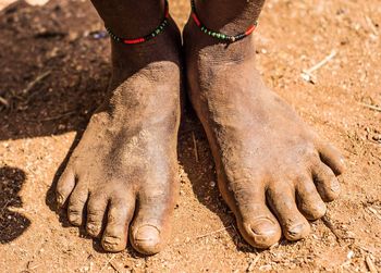 Low section of woman with dirty legs standing on road