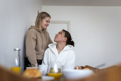 Loving lesbians looking at each other by white wall