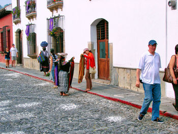 Rear view of people walking on street amidst buildings