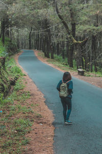 Full length of woman standing on road in forest