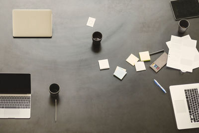 Directly above shot of technologies with coffee mugs and adhesive notes on table