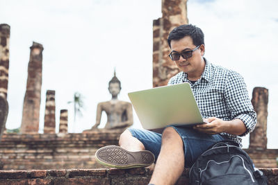 Asian tourist working and using laptop at sukhothai historical park, thailand