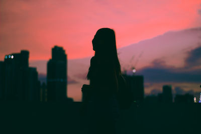 Rear view of silhouette woman against sky during sunset