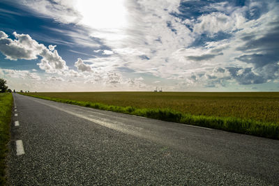 Road amidst field against sky