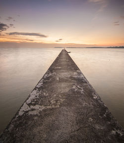 Jetty in sea against cloudy sky