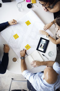 Overhead view of architects discussing over blueprints at creative office