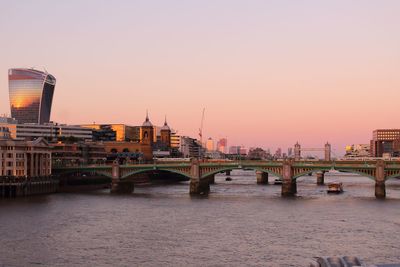 Bridge over river in city against clear sky