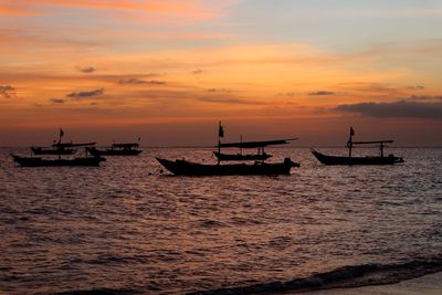 Silhouette boats in sea against sky during sunset