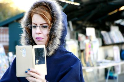 Woman wearing warm clothing using smart phone in city