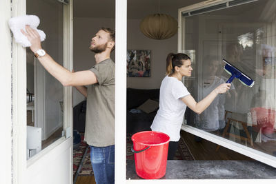 Couple cleaning window together at home