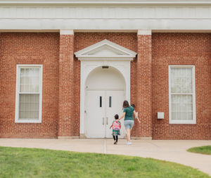 Rear view of woman walking in front of building