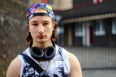 Portrait of young man wearing headphones while standing outdoors
