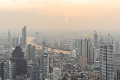 Aerial view of buildings in city against sky during sunset