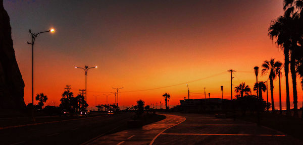 Silhouette street against sky during sunset