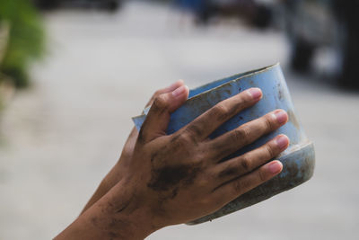 Close-up of hand holding container while begging