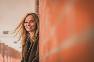 Portrait of smiling beautiful woman with blond hair standing by architectural column