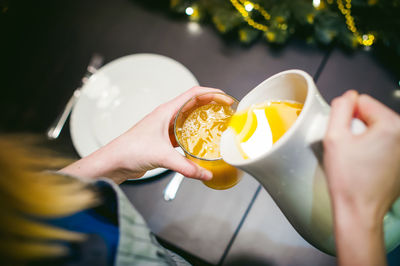 Cropped hands of woman pouring juice in drinking glass