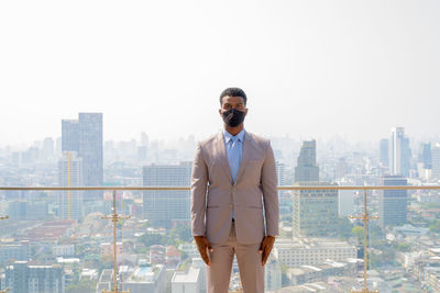 Full length of man standing by buildings in city against sky