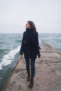 Beautiful woman walking on the beach with seagulls in winter time. free spirit concept person