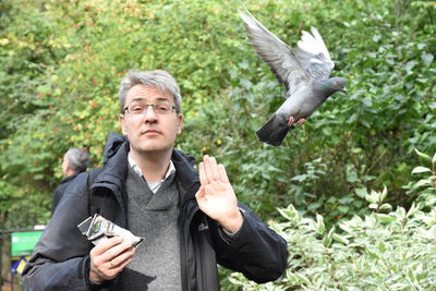 Portrait of man gesturing by flying bird