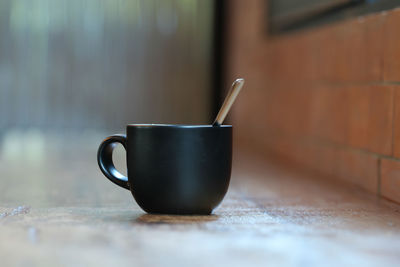 Close-up of coffee cup on table against wall