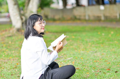 Side view of a young woman sitting on field