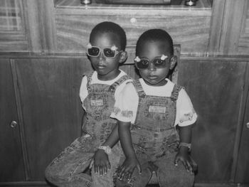 Portrait of brothers wearing sunglasses while sitting on chair