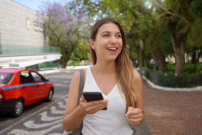 Brazilian woman holding her smartphone looking to the side, porto alegre, rio grande do sul, brazil