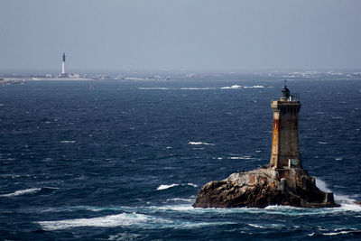 Lighthouse by sea against sky