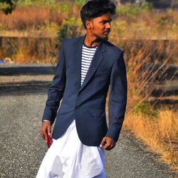 Young man looking away while standing on road