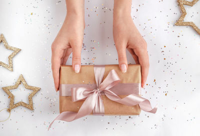 Low section of woman holding gift against white background