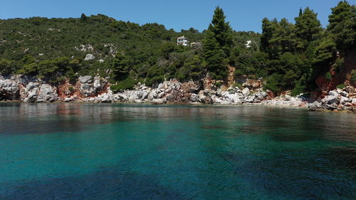 Scenic view of rocks by trees against sky