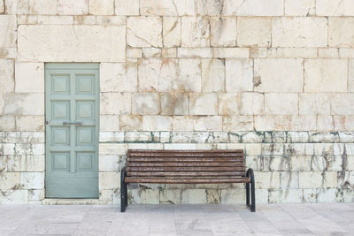 Empty bench against brick wall