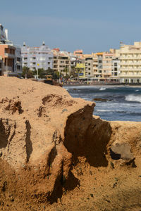Scenic view of beach by buildings against sky