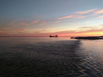 Boats in calm sea at sunset