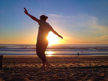 Man standing on beach against sky during sunset