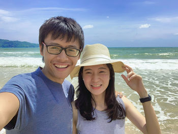 Portrait of happy couple at beach against sky