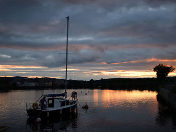 Boat moored in river against sky during sunset