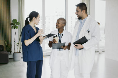 Smiling multiracial healthcare workers discussing while standing at hospital