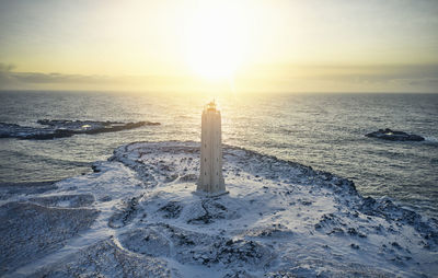 Lighthouse on seashore in evening in winter