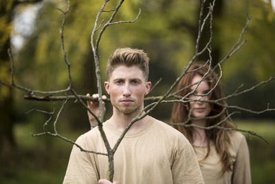 Portrait of young man and woman holding dead plants