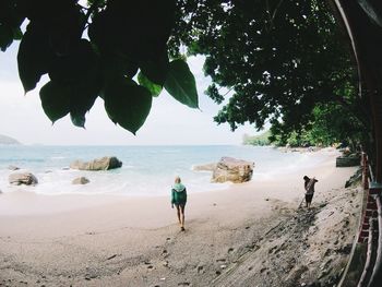 Rear view of people on beach against sky