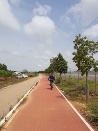 Rear view of man riding motorcycle on road against sky