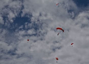 Low angle view of paragliding against cloudy sky